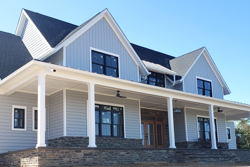 Gray board and batten house with white trim and black windows