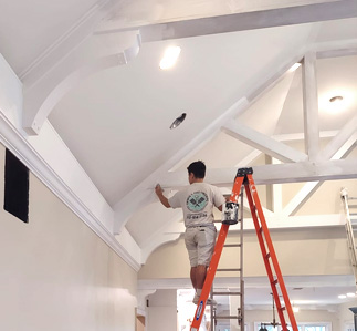 Painter inside on ladder painting trim.